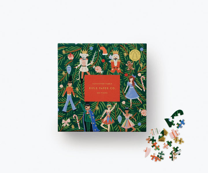 Green puzzle box with characters from the Nutcracker and various Christmas items, such as candy cane, and gingerbread men, and a few puzzle pieces on the side. 