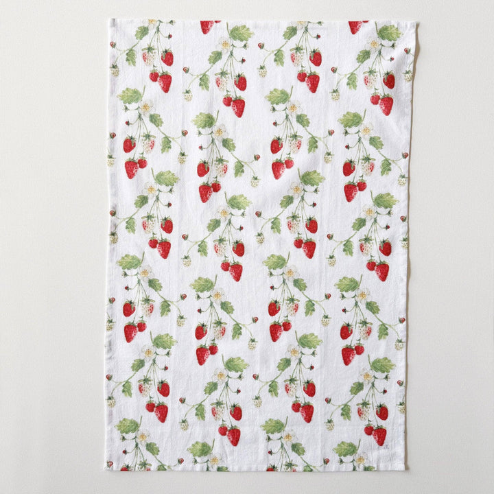 Kitchen towel laid flat to show repeated pattern of stems with strawberries.