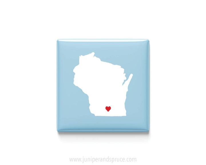 A square light blue magnet featuring a white silhouette of the state of Wisconsin in white with a small red heart near the bottom center.