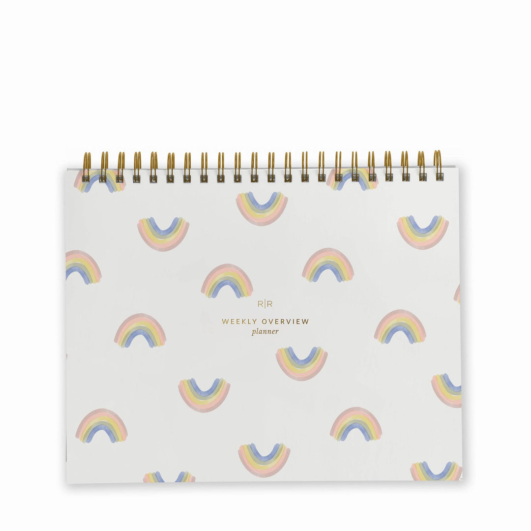 Cover of weekly planner with a pattern of small rainbows and a gold spiral binding at top.