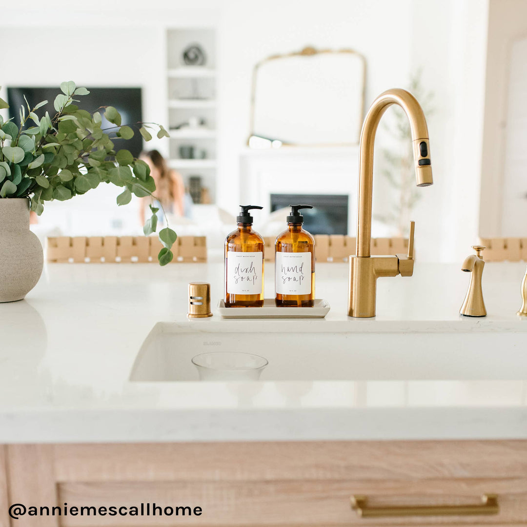 White matte tray holding soap containers at kitchen sink.