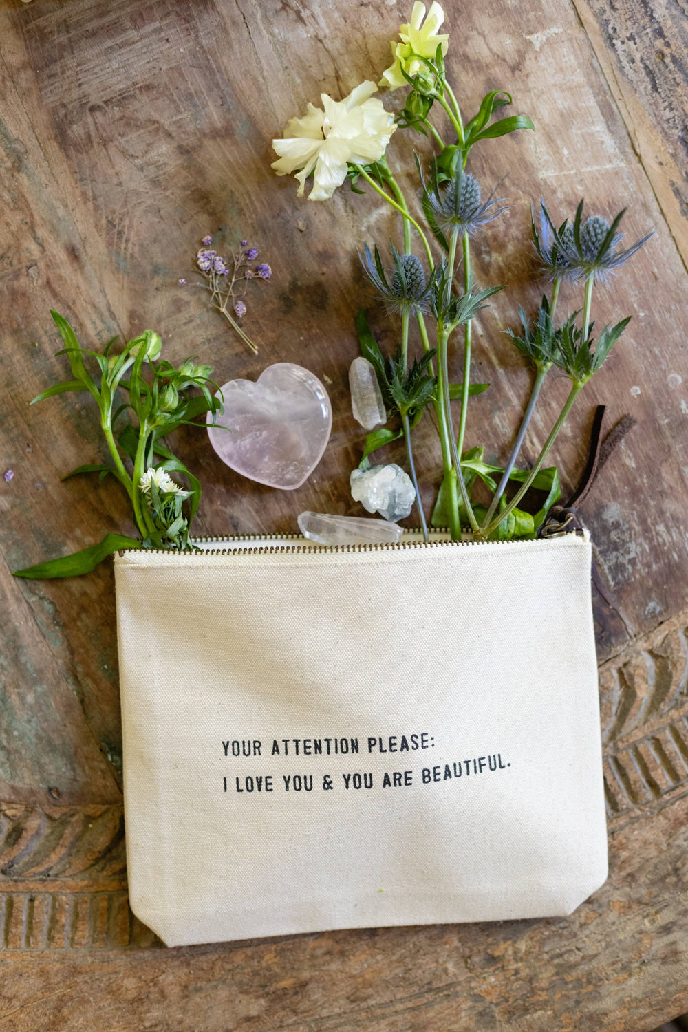 Wild flowers in an open zipper pouch on a wooden table.