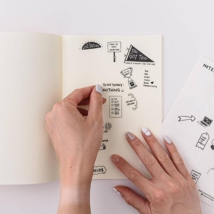 Hand placing a sticker on a page.