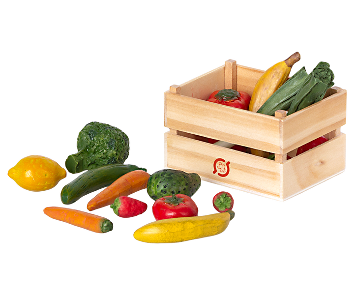 Crate containing vegetables next to its contents: broccoli, lemon, cucumber, carrot, pepper, squash, tomato.