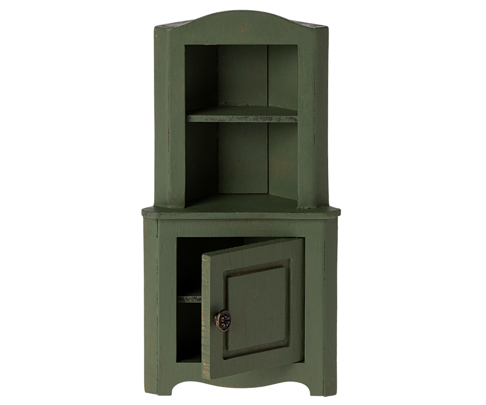 Green corner cabinet with top section with shelf and a door in the bottom section slightly ajar.