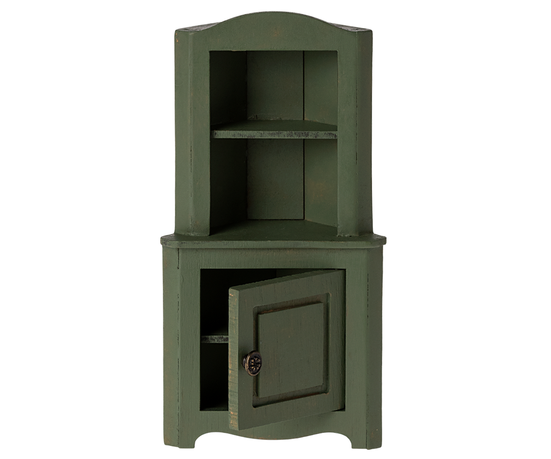 Green corner cabinet with top section with shelf and a door in the bottom section slightly ajar.
