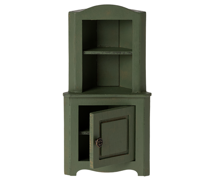 Green corner cabinet with top section with shelf and a door in the bottom section slightly ajar.