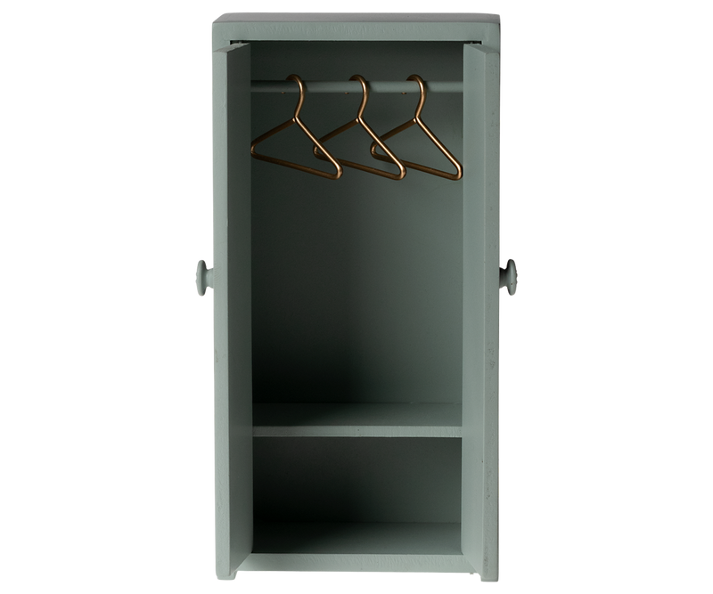 Tall green cabinet with open doors showing three hangers on the rod and a shelf near the bottom.