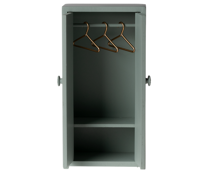 Tall green cabinet with open doors showing three hangers on the rod and a shelf near the bottom.