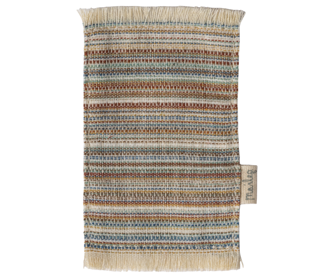 Striped fabric rug in blues and browns with fringe at the end on the short sides 