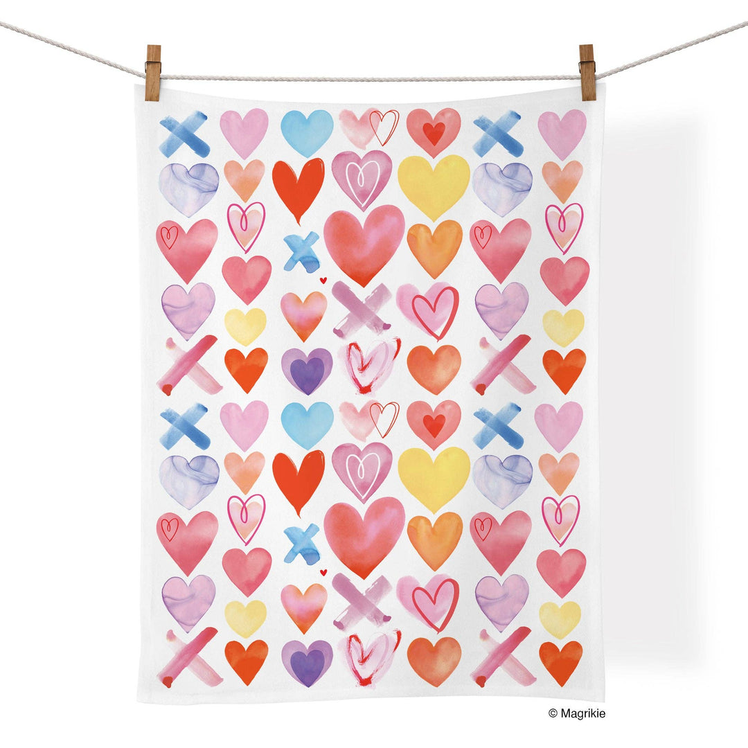 Tea towel with colorful pattern of hearts and Xs hanging on a line.