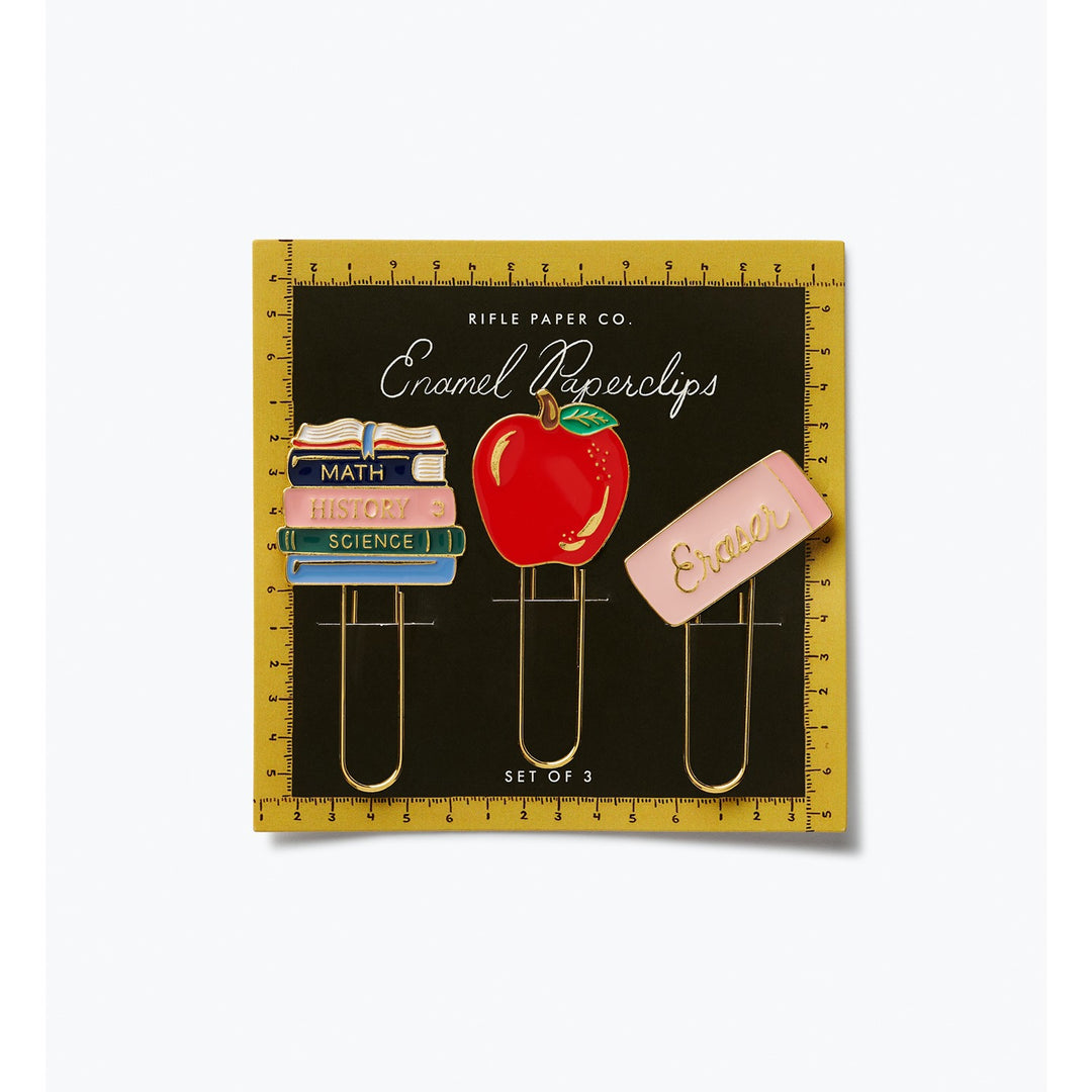 Set of three enamel paperclips with a stack of books, an apple, and an eraser on packaging with a ruler border.