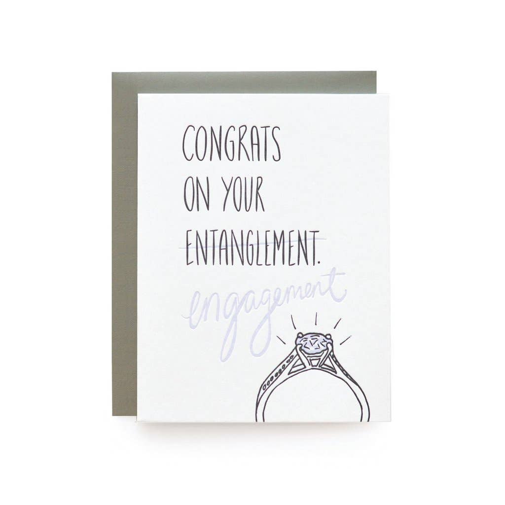 Dark grey text on  white cardstock. The word "entanglement" is crossed out, replaced with the word "engagement" in light grey over a drawing of engagement ring.