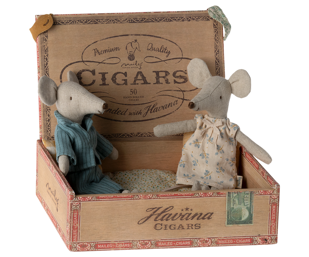 Mum mouse wearing an off-white nightgown with flower pattern sitting next to Dad mouse, wearing blue striped pajamas, in a cigar box.
