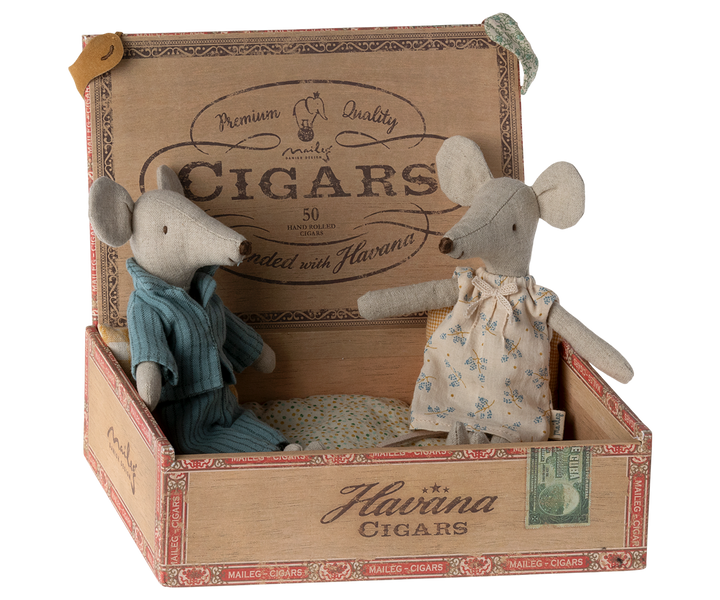 Mum mouse wearing an off-white nightgown with flower pattern sitting next to Dad mouse, wearing blue striped pajamas, in a cigar box.