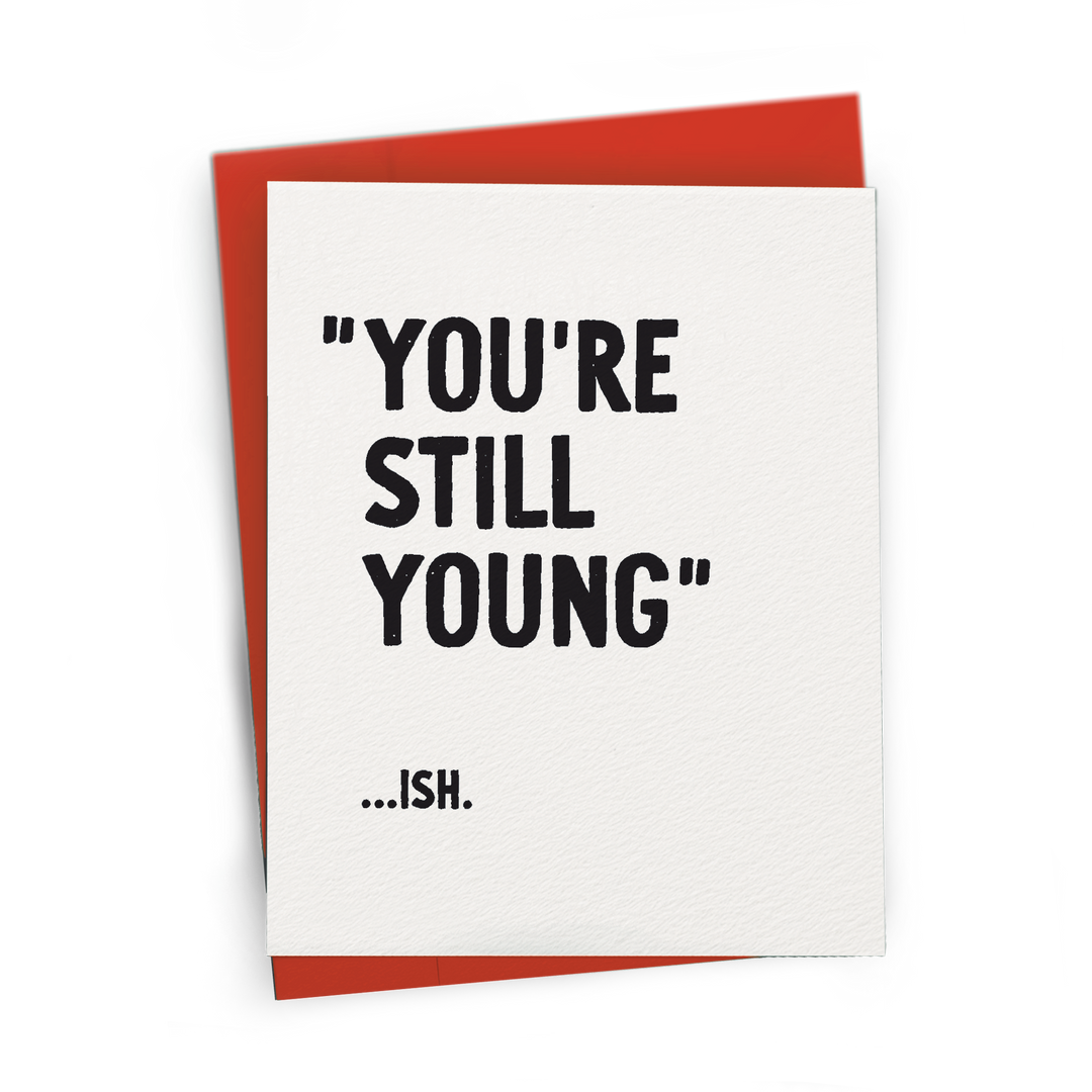 Greeting card with 'You're Still Young...Ish.' text on a white background with red envelope.