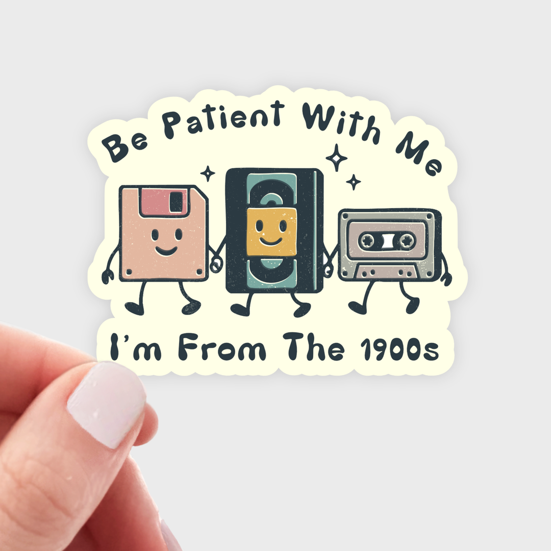 Sticker with cartoon images of a floppy disk, cassette tape, and video game cartridge, each with arms and legs, and with the text 'Be Patient With Me I'm From The 1900s' 