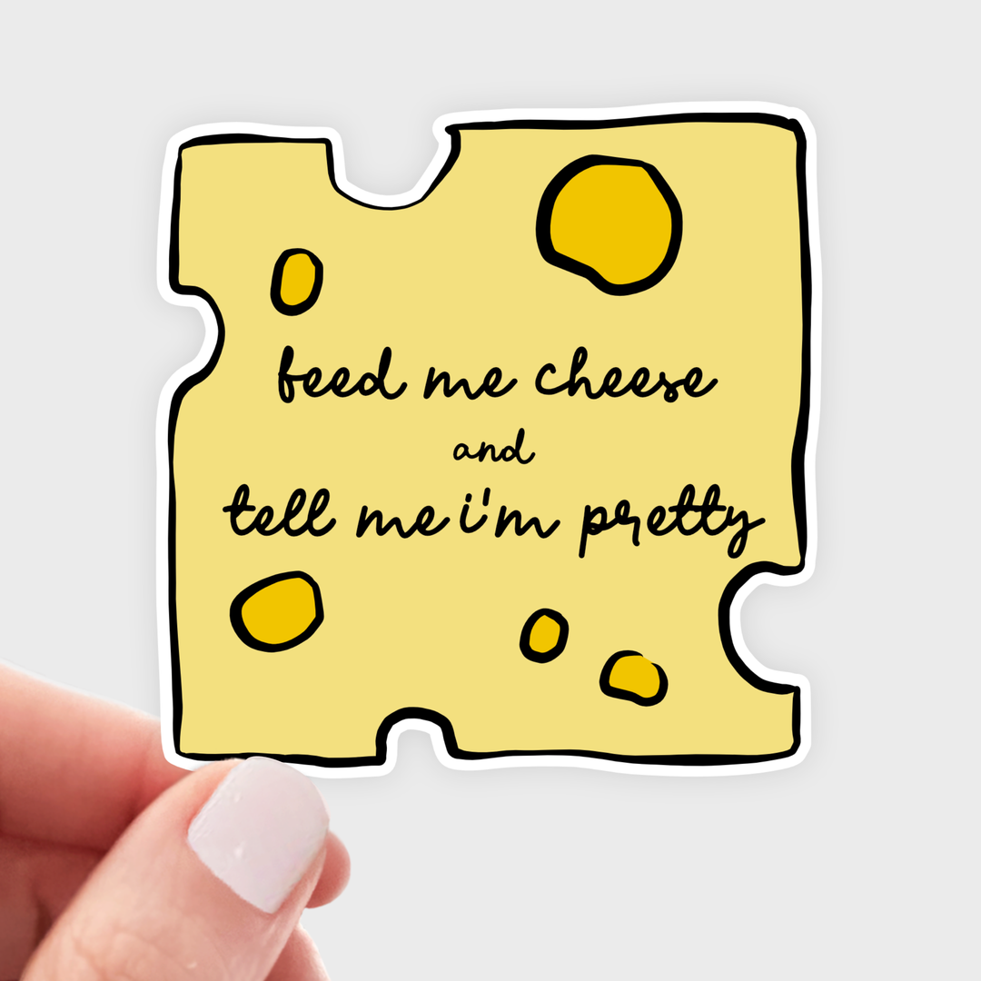 Yellow square sticker in the shape of a chunk of Swiss cheese, with the text 'feed me cheese and tell me I'm pretty' in black in the center.