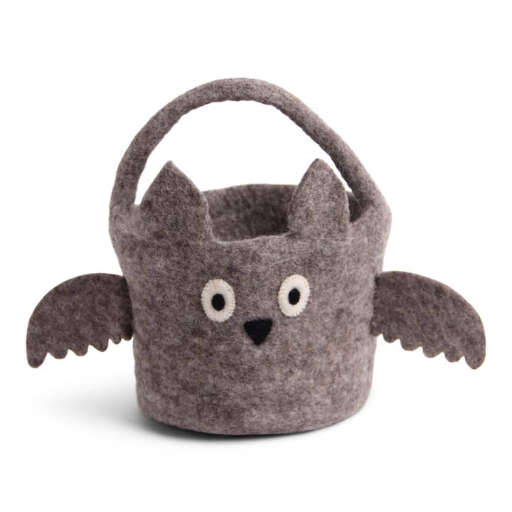 A gray felt basket designed to look like a bat with dark gray wings and a face with two eyes and a black triangle for a nose, handmade and suitable for holding treats for Halloween.