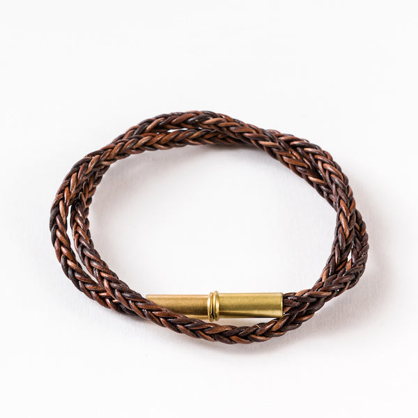 Brown double-wrapped braided leather bracelet with a brass cylindrical clasp.