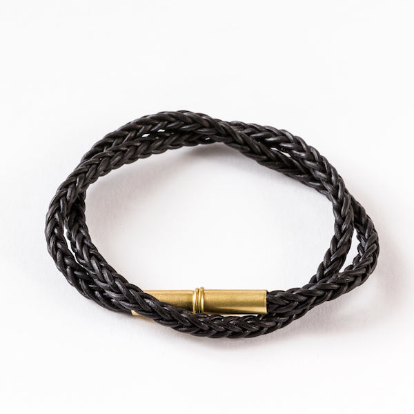 Black double-wrapped braided bracelet with a brass cylindrical clasp.