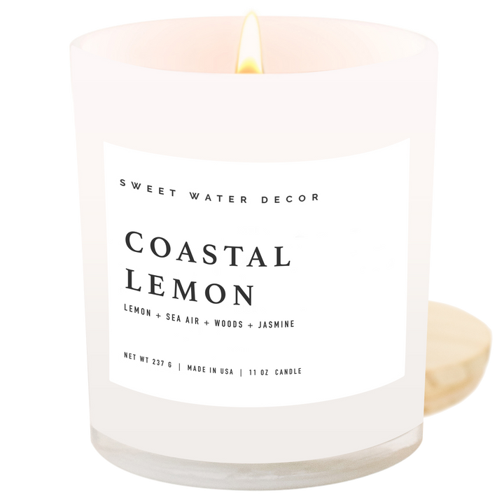 Lit candle in opaque off-white glass container; white label with black text.