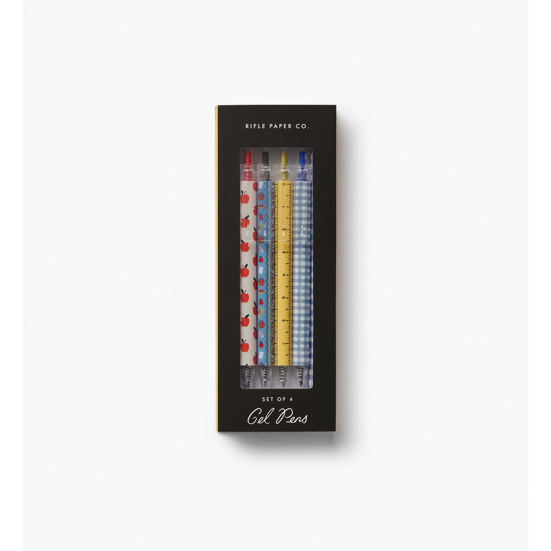 Four pens in a box. The decorations on the pens are: apples; small objects; a ruler; and gingham checks.