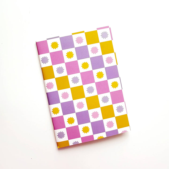 Notebook with a colorful checkered pattern in gold, lavender and rose stars and quares