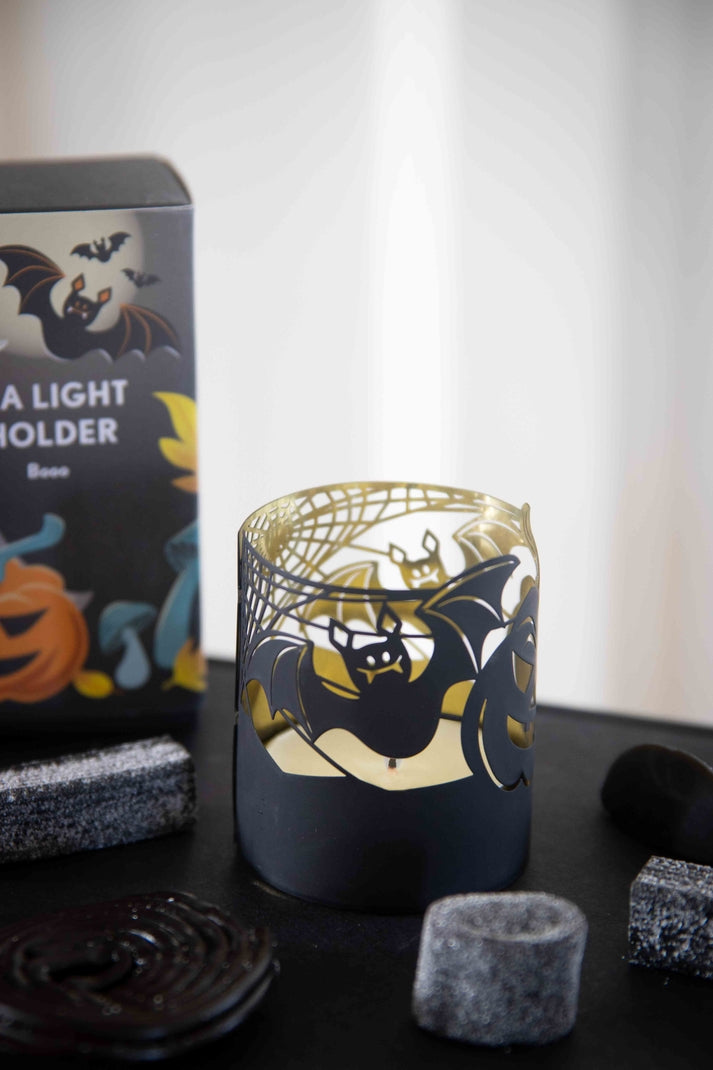 Candle holder shown on a table with a lit candle inside. 