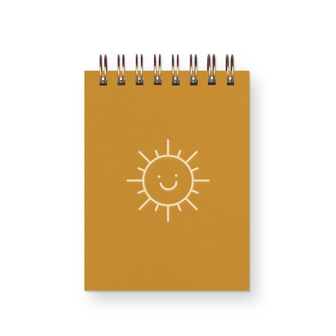 Spiral bound mini-notebook with line drawing of smiling sun face