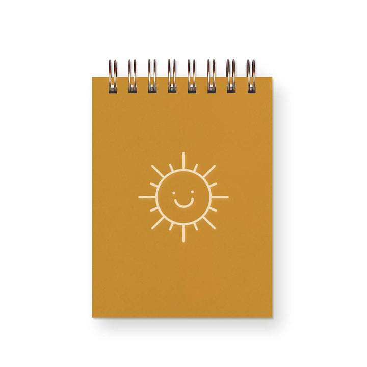 Spiral bound mini-notebook with line drawing of smiling sun face