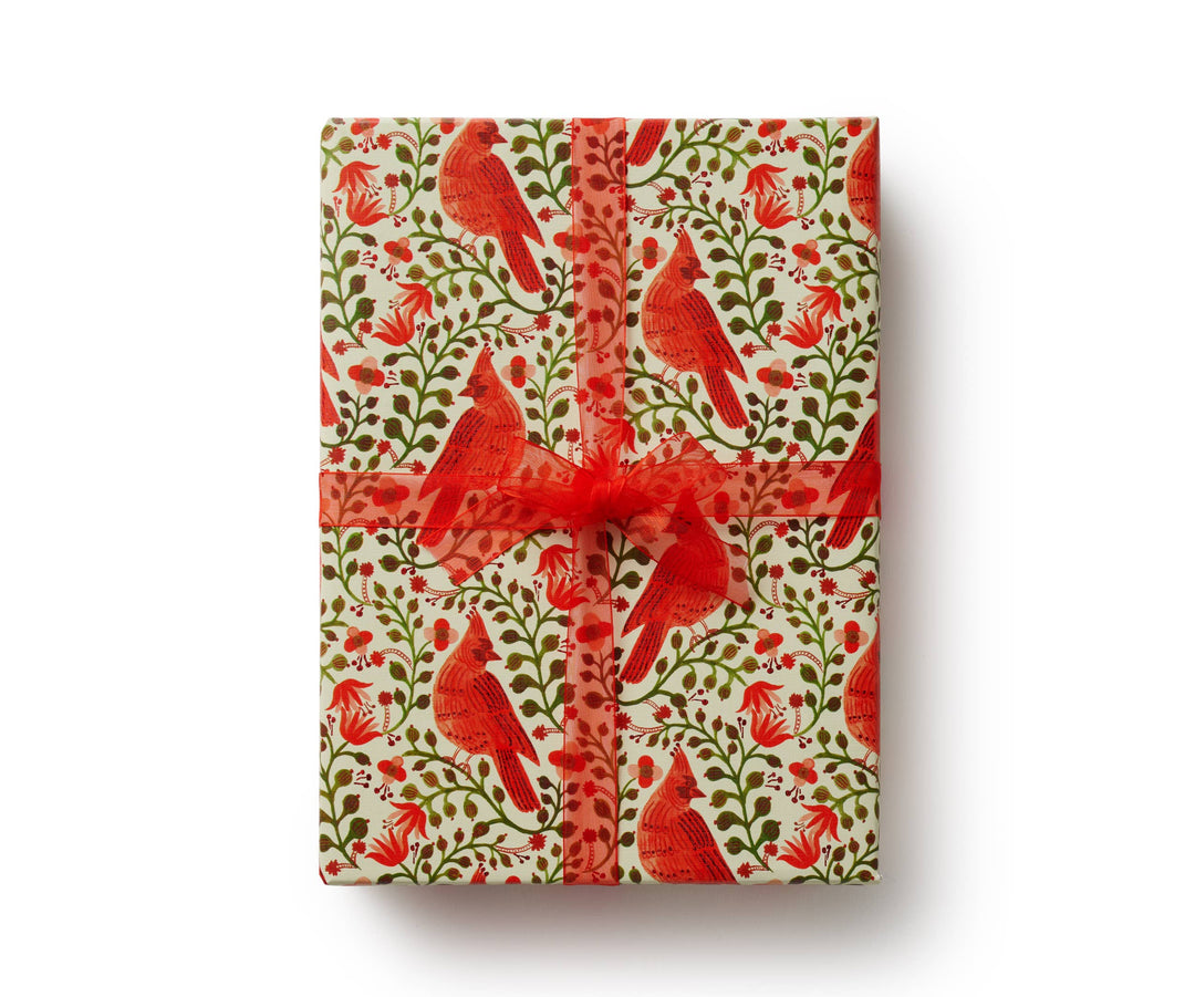 Giftwrapped box with pattern of cardinals and florals, tied with a red ribbon.