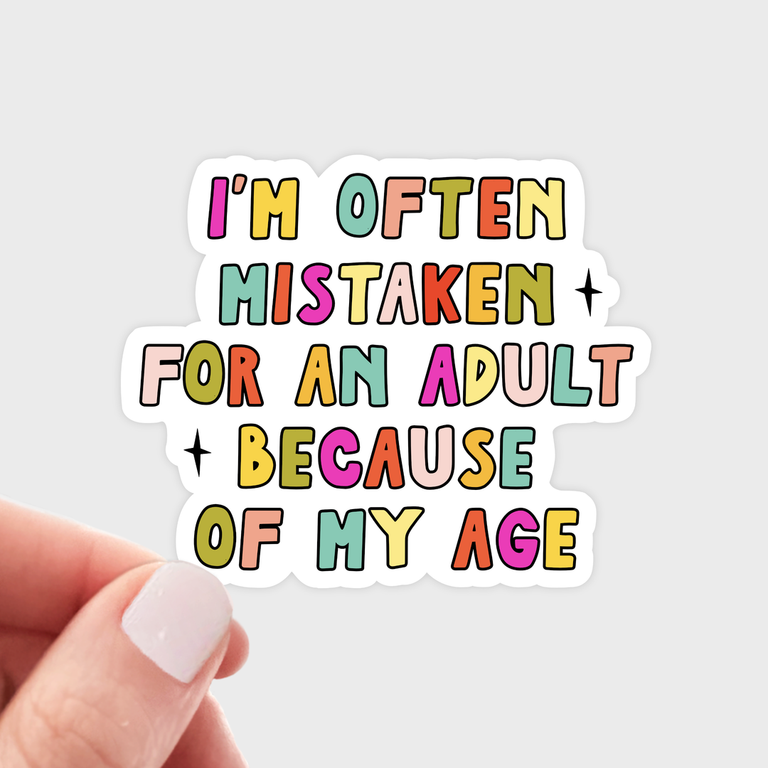 Hand holding a sticker with colorful text 'I'm often mistaken for an adult because of my age'