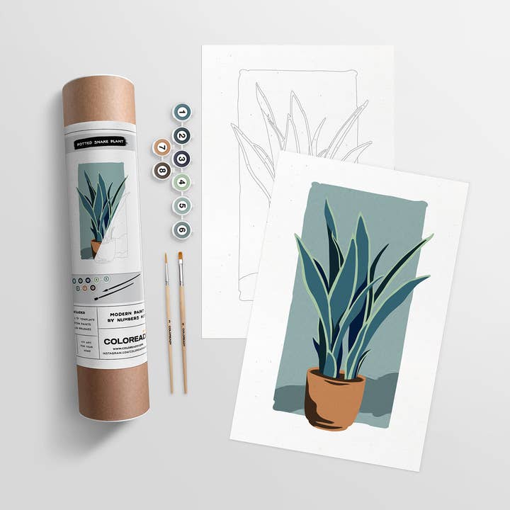 Kit tube, with label showing contents, next to the paint tubes, paintbrushes, and the template and completed painting.