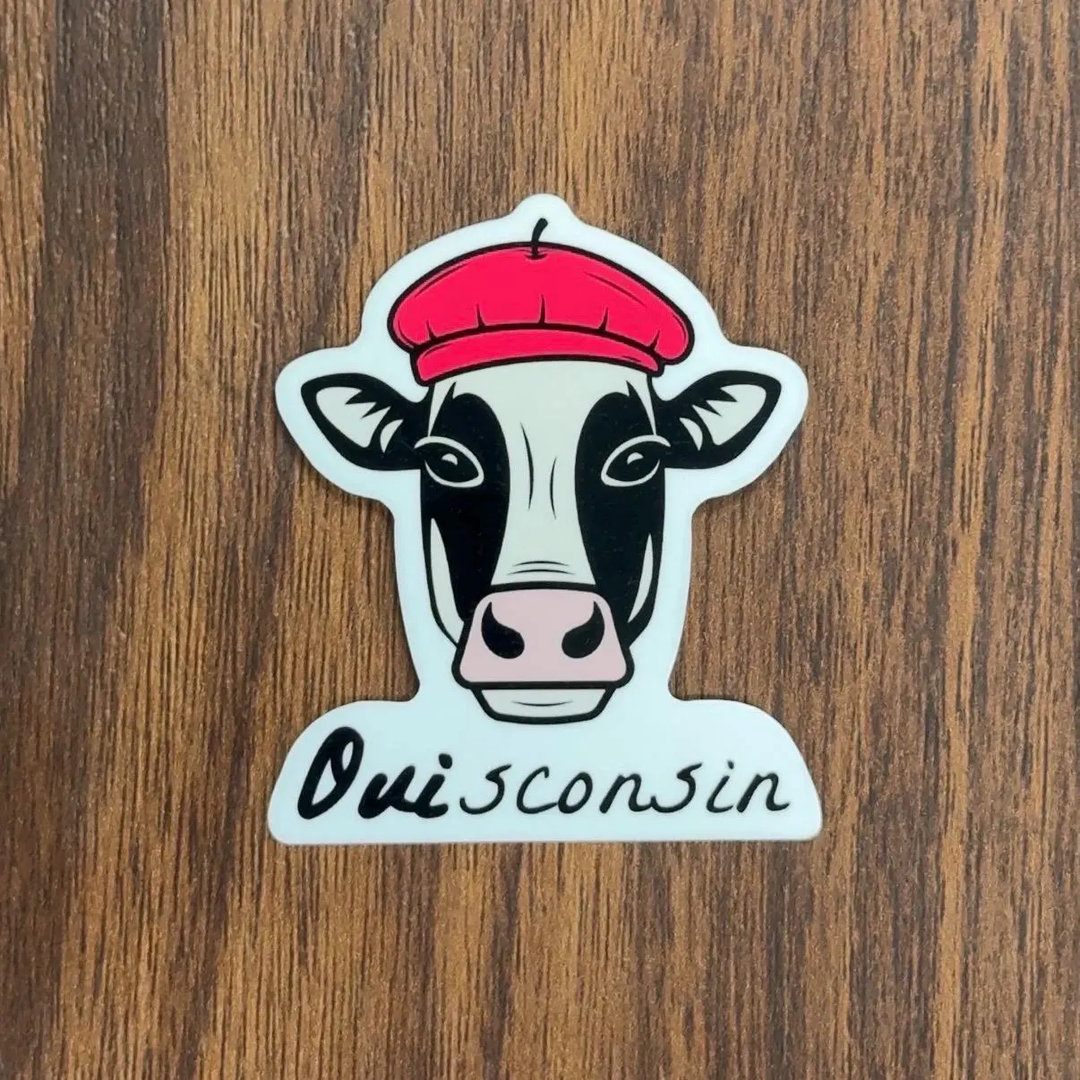 Cartoon illustration of a cow's head wearing a red beret, with the word 'Ouiconsin' written below in black script.