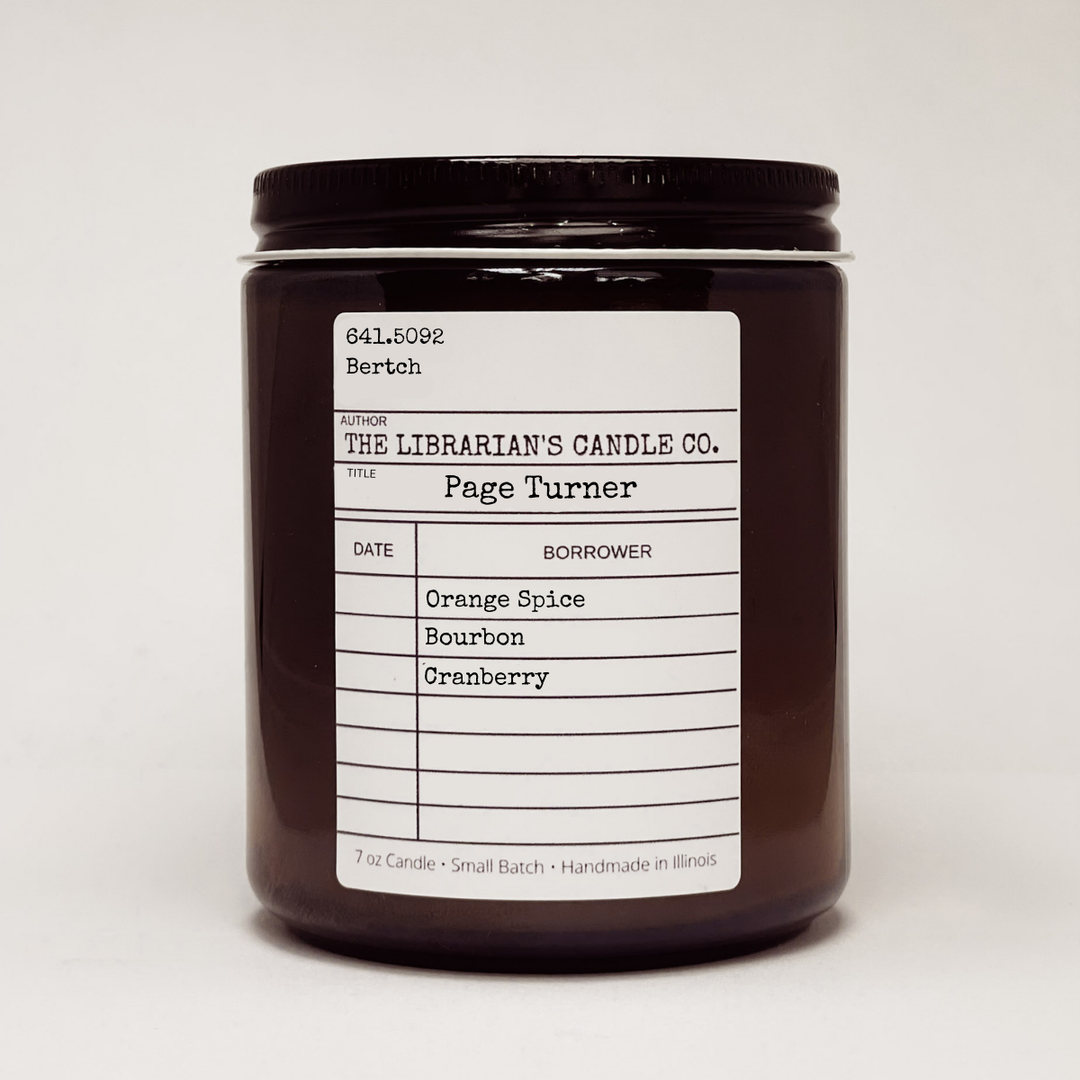 Candle jar with a label in the design of a library due date slip for the book 'Page Turner' detailing scent notes: orange spice, bourbon, cranberry. 