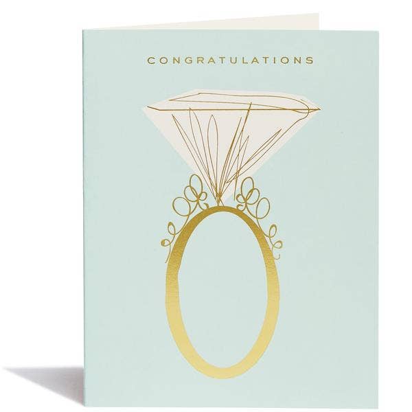 Light blue cardstock with gold lettering and a drawing of an engagement ring that fills most of the card.