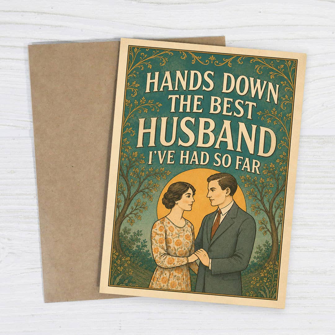 A rectangular greeting card with a kraft paper envelope. The card has a vintage-style illustration of a couple under decorative trees, with the text 'HANDS DOWN THE BEST HUSBAND I'VE HAD SO FAR.