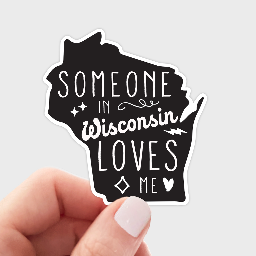 Sticker shaped like the state of Wisconsin with text 'Someone in Wisconsin loves me' in white letters on black text.
