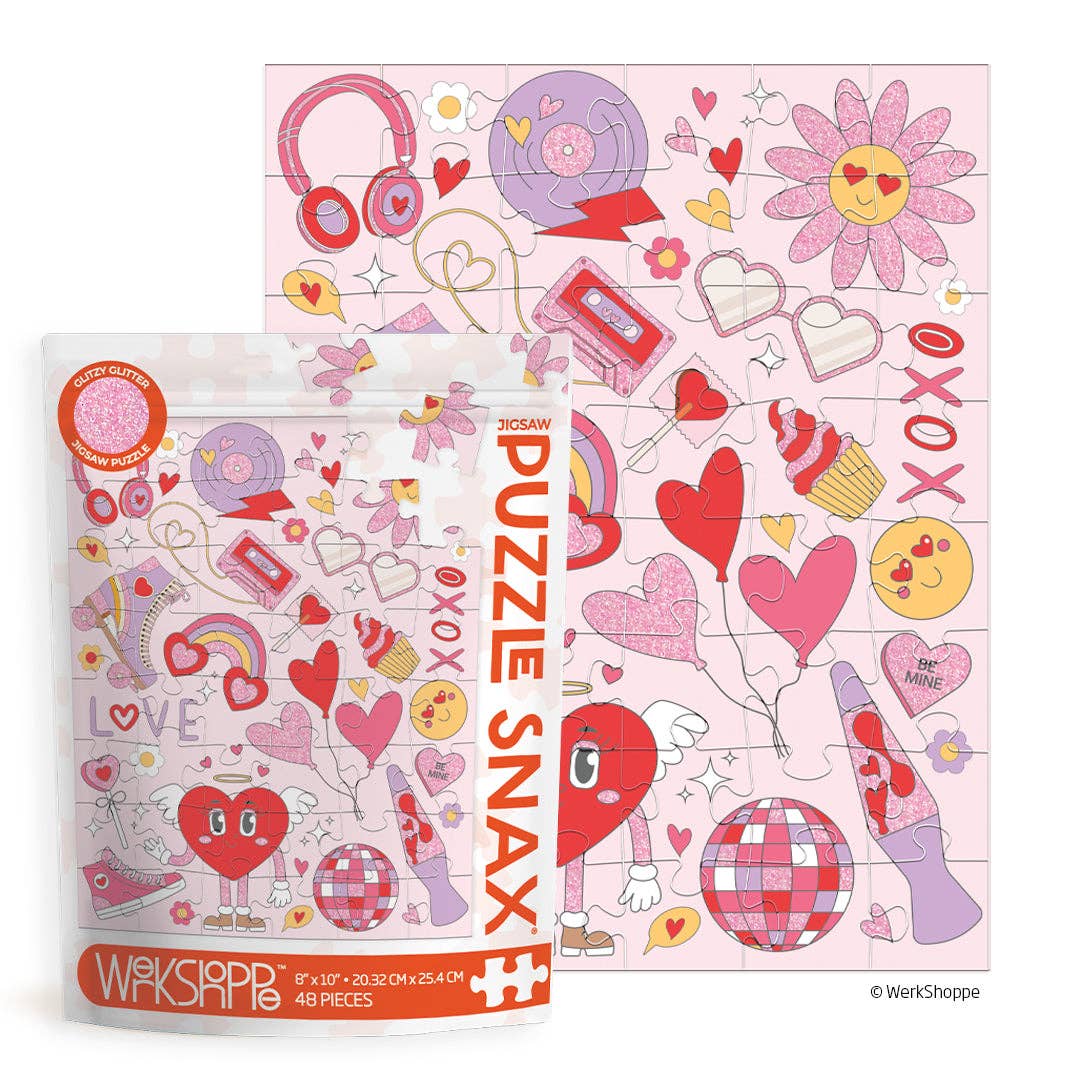 Puzzle Snax packaging in front of a completed puzzle with hearts, disco balls, "xoxo" and other retro symbols, in pinks and reds.