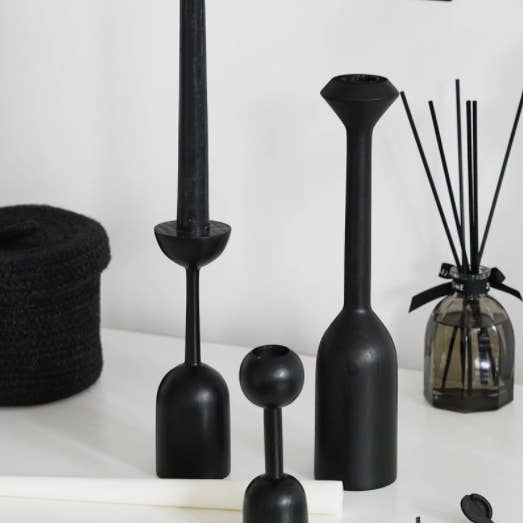 Three black wood candlesticks of different heights.