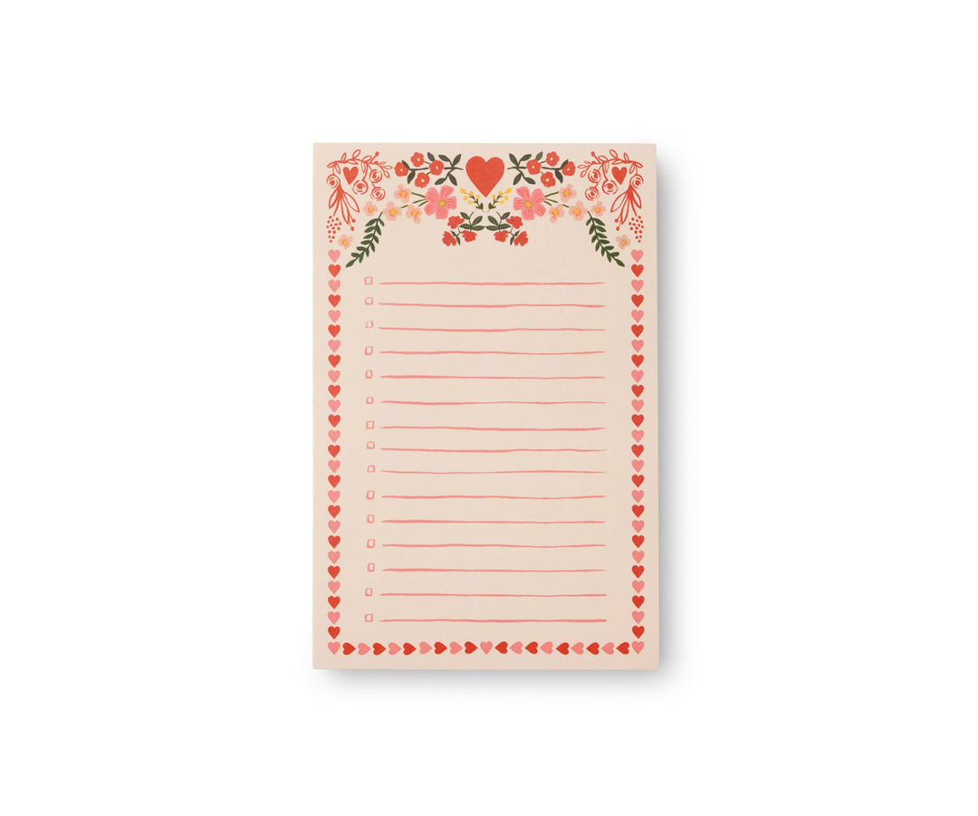 Notepad with border of red and pink hearts and a heart and flower decoration at the top, with checkboxes next to lines for notes, on a light pink background.