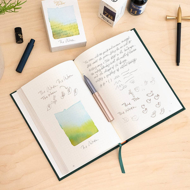 Open notebook with the pen lying on top. Pieces of the pen surround the notebook.