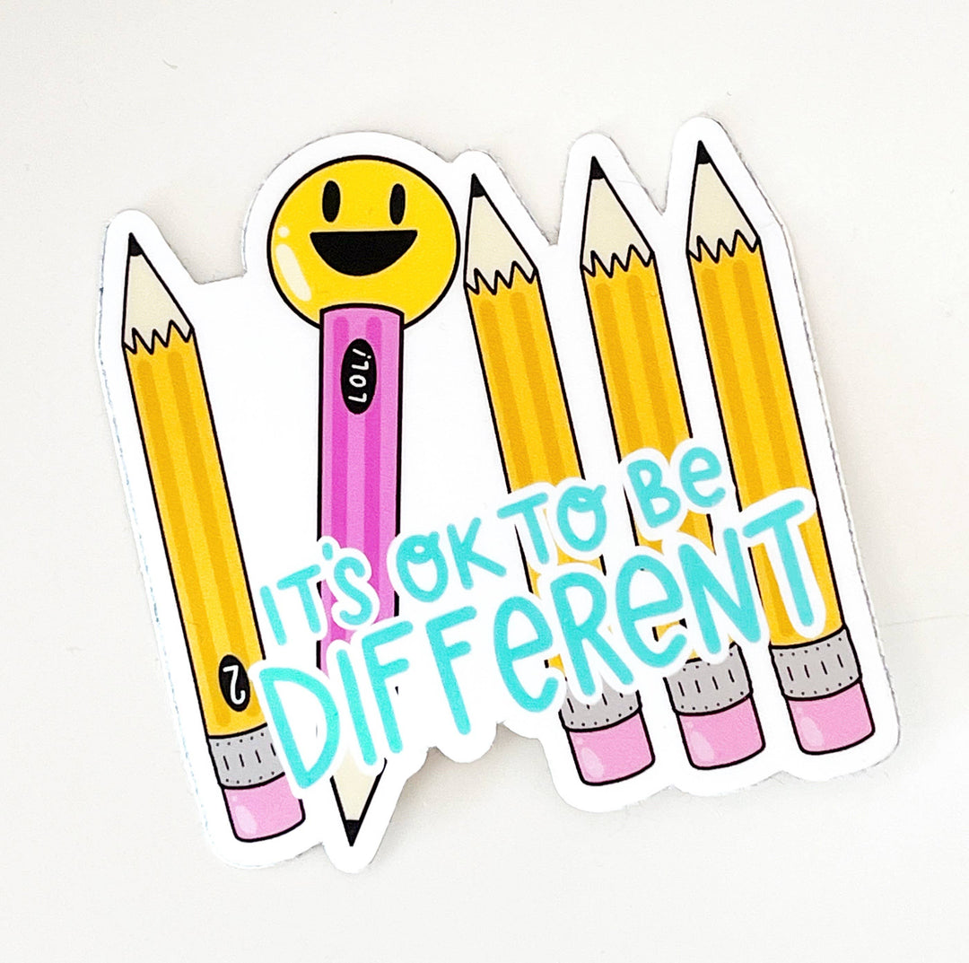 Sticker with pencils and a smiley face with text 'It's ok to be different' 
