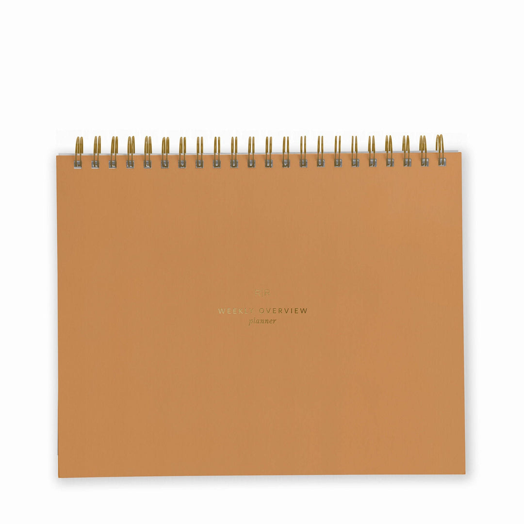Cover of weekly planner in mustard with gold spiral binding at top.