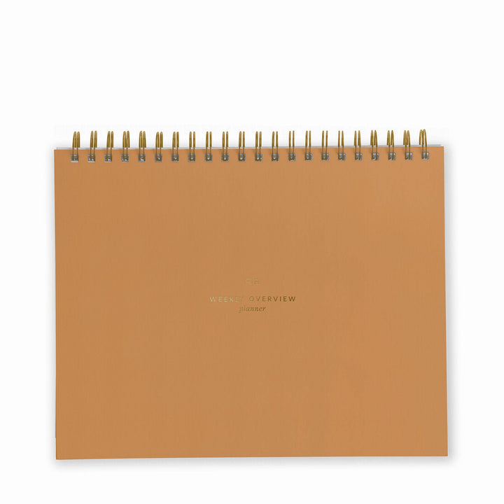 Cover of weekly planner in mustard with gold spiral binding at top.