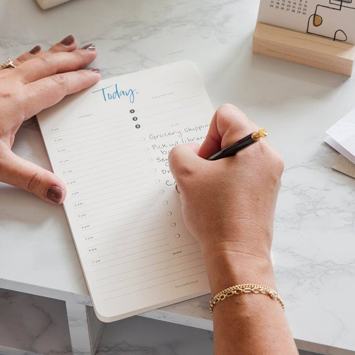 Person writing in the  planner.