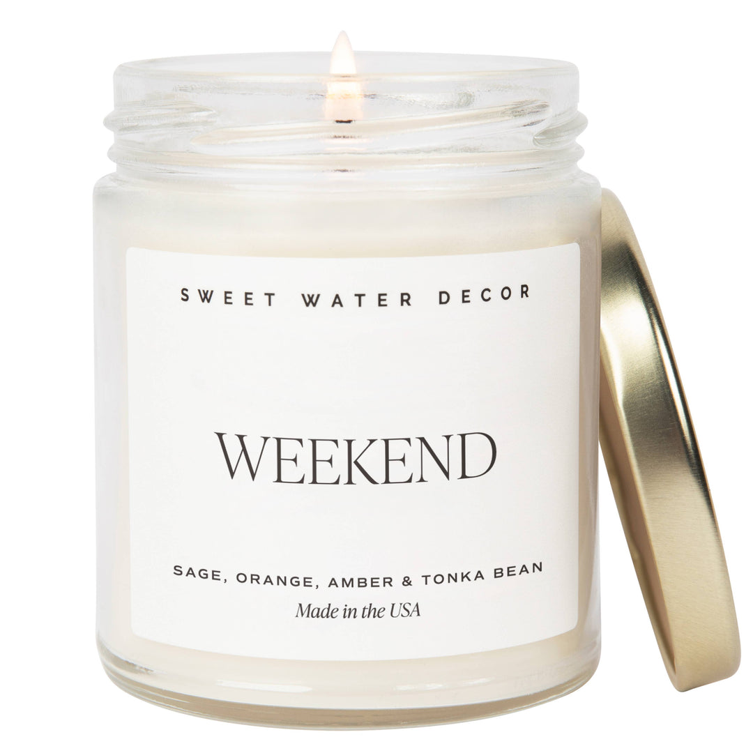 Lit candle in a white opaque jar with gold tone lid and black text on a white label.