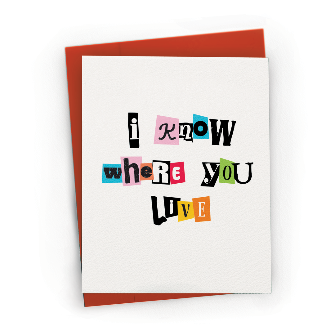 A white greeting card with a colorful typographic design reading 'i know where you live' in mixed black, pink, blue, red, green, and orange lettering, shown with a rust-red envelope.