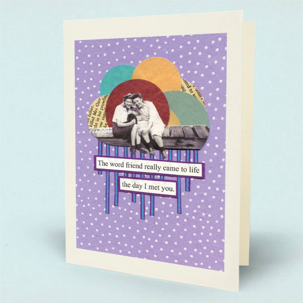 A greeting card with a white border and a purple polka-dot background, featuring a retro collage of two people sitting on a bench beneath overlapping colorful circles. Text on the card reads, 'The word friend really came to life the day I met you.